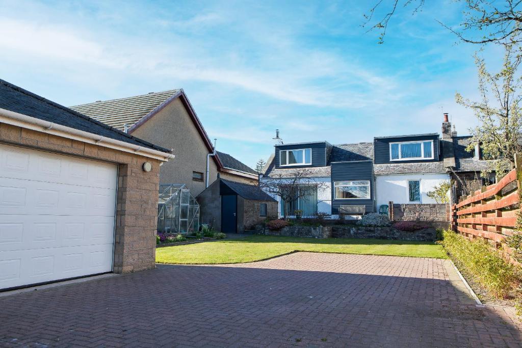 a house with a white garage door on a driveway at The Albatross in Panbride