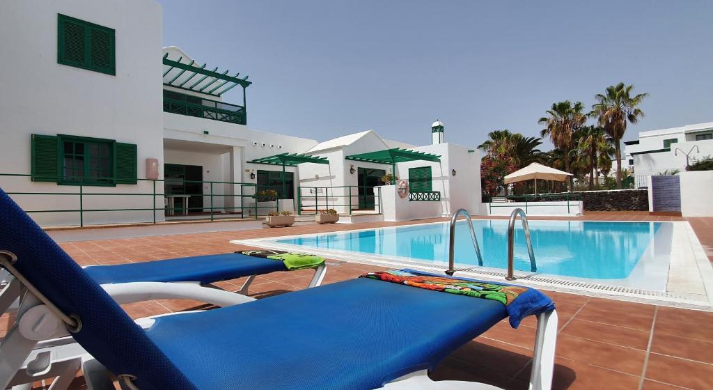 a swimming pool with blue chairs next to a building at Apartamentos Las Palmeras I in Puerto del Carmen