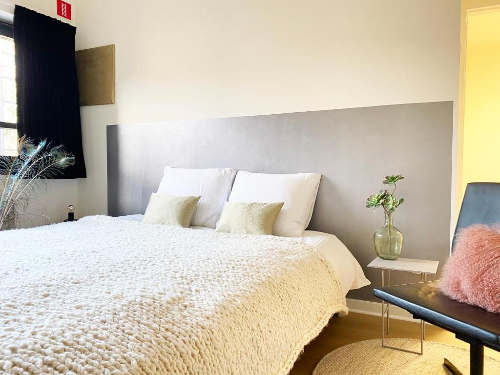 1 dormitorio con 1 cama grande con almohadas blancas en B&B Expo House, en Amberes