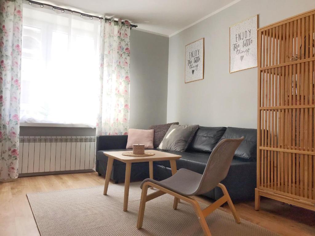 ein Wohnzimmer mit einem blauen Sofa und einem Tisch in der Unterkunft Pastelove mieszkanie przy centrum - bezkontaktowo in Bielsko-Biała