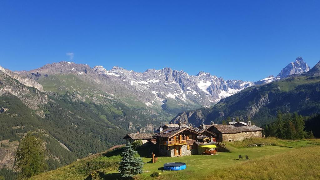 a house on a hill with mountains in the background at Chalet Le Lis in Valtournenche
