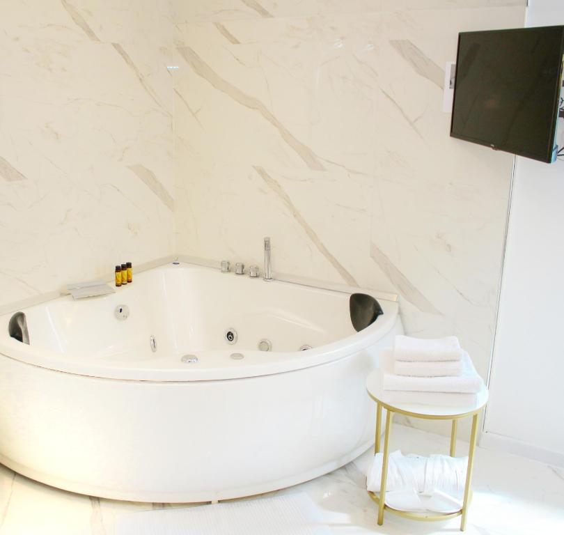 a white bath tub in a white bathroom with a stool at Seven Luxury Suites in Belgrade