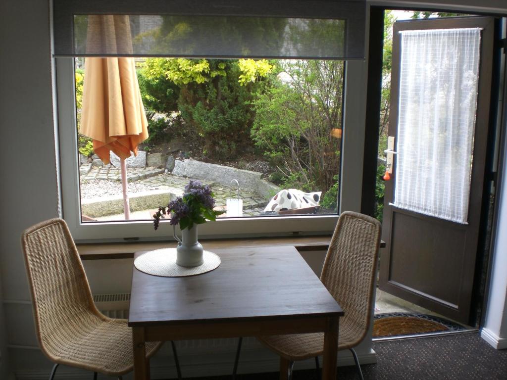 einen Tisch und Stühle mit einem Hund vor dem Fenster in der Unterkunft Zur Weide in Boltenhagen