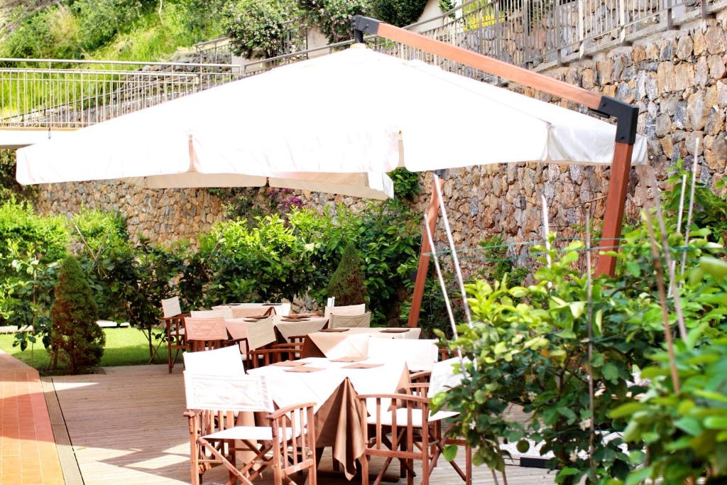 a group of tables and chairs with a white umbrella at Baia Blu RTA Residence in Lerici