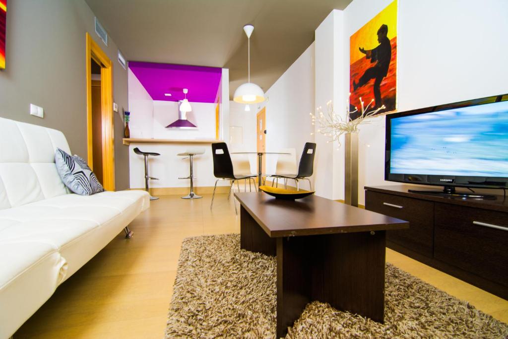 ein Wohnzimmer mit einem weißen Sofa und einem Flachbild-TV in der Unterkunft Apartamentos 16:9 Suites Almería in Almería