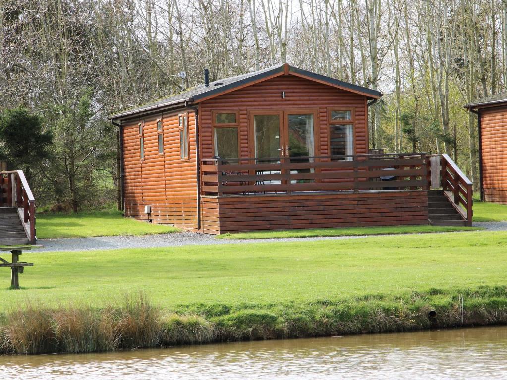 a wooden cabin next to a body of water at Oak Lodge in Hadnall