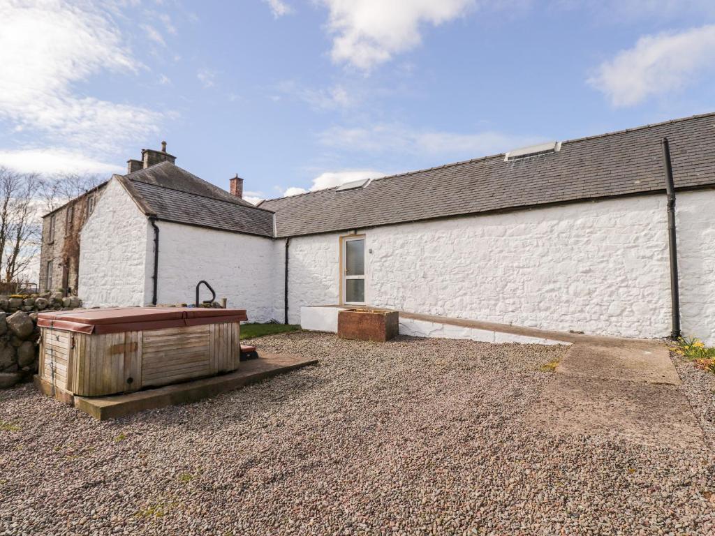a white building with a tub in front of it at Shetland Cottage in Dalbeattie
