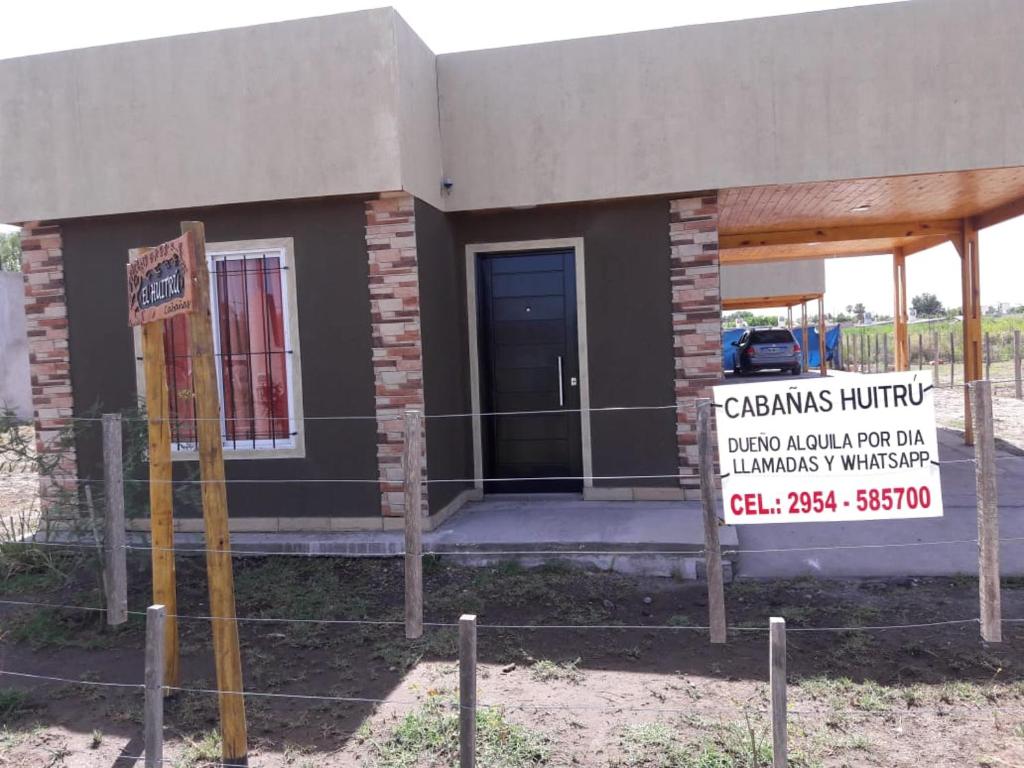 una pequeña casa con un cartel delante en CABAÑAS HUITRU en General Alvear