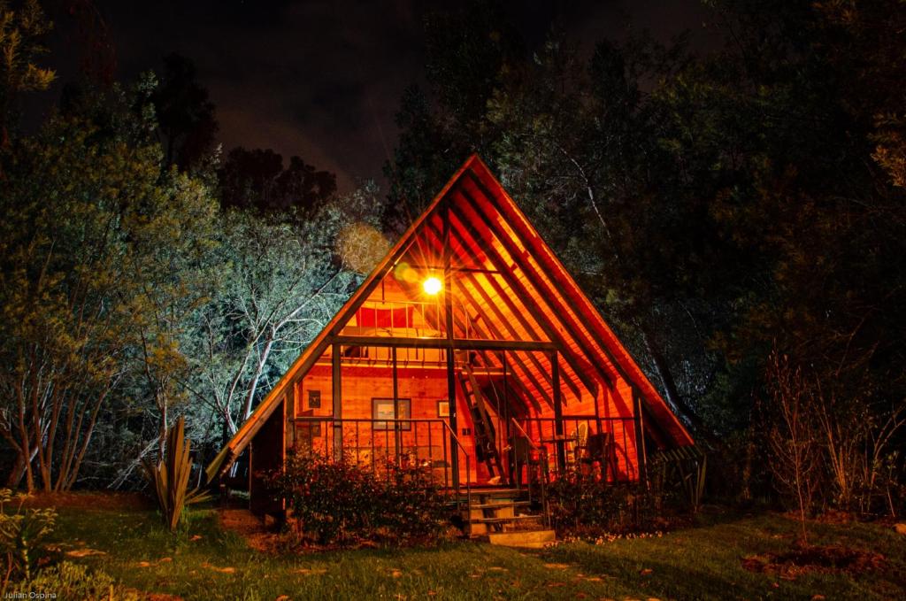 Cabaña de madera grande con luz en la parte delantera en Glamping Los Ángeles, en Guasca