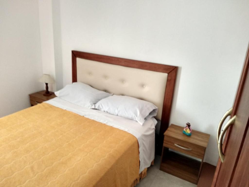 1 dormitorio con 1 cama con cabecero de madera y mesa en Brisas del Parque en Salta