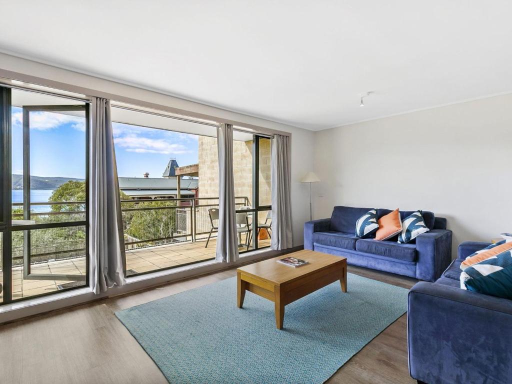 uma sala de estar com um sofá azul e janelas grandes em Apartment 29 Pacific Apartments em Lorne