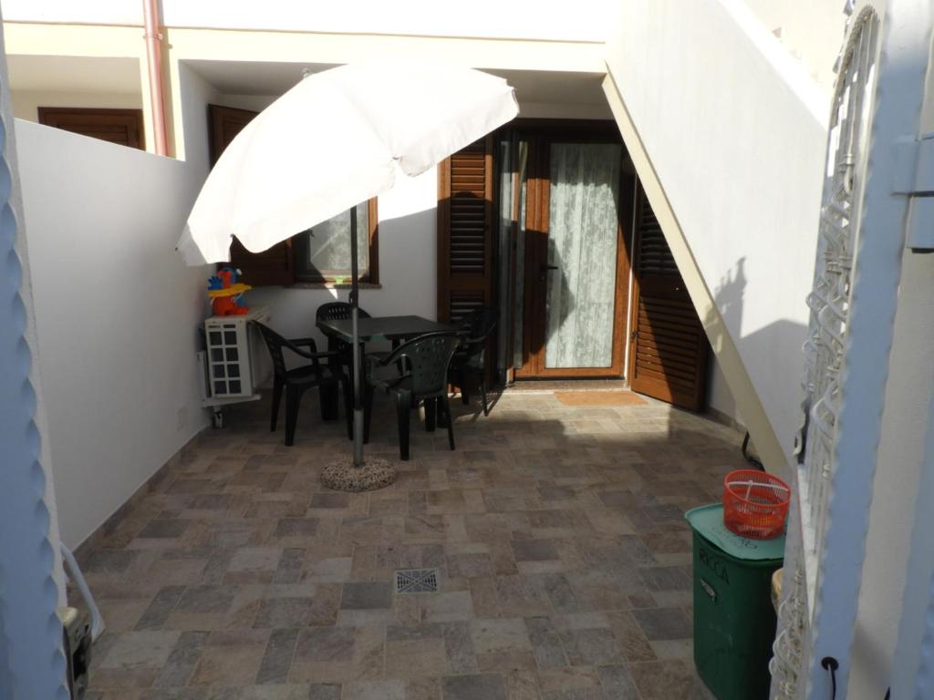 a patio with a table and a white umbrella at Baby House Calasetta - IUN P5263 in Calasetta