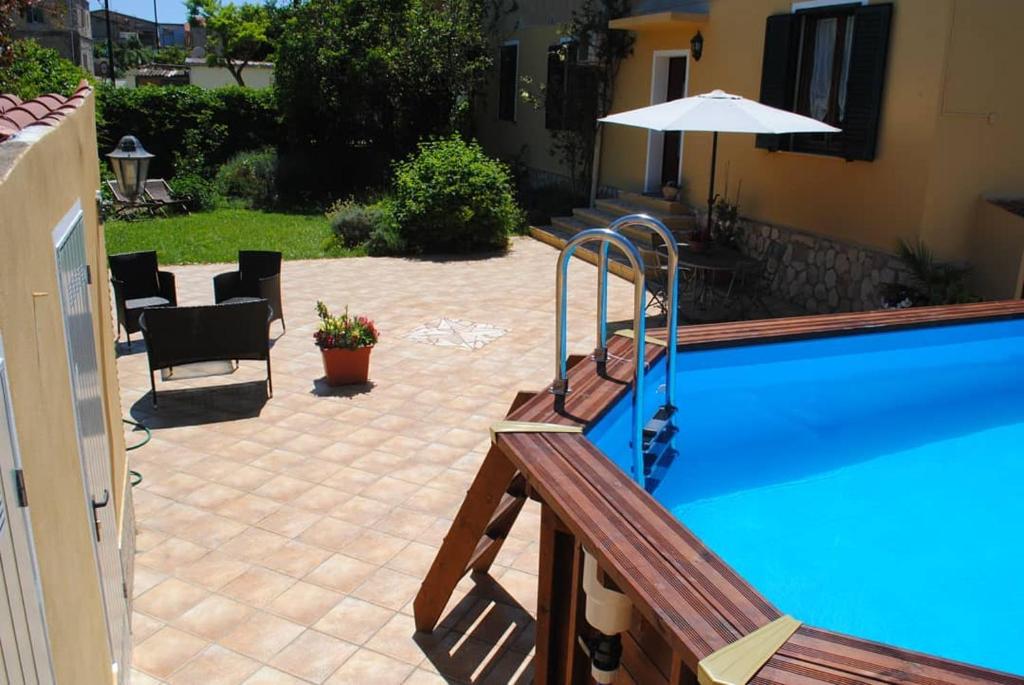 una piscina con sombrilla y un patio en B&B Del Viale en Bacu Abis
