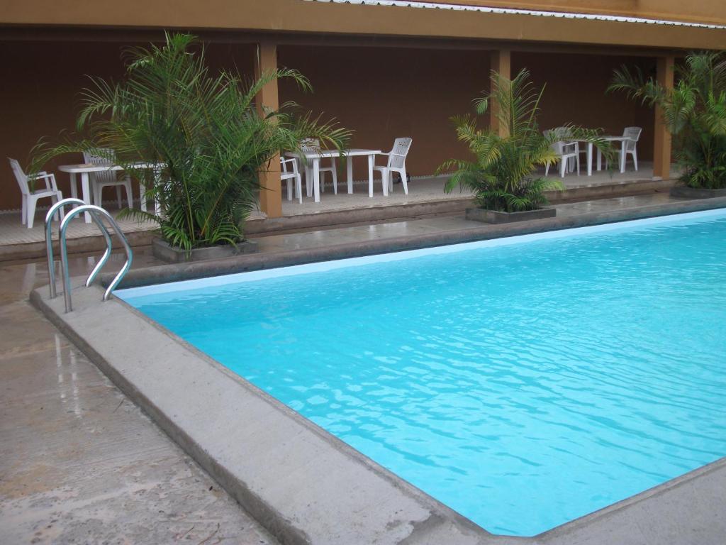 a swimming pool with a table and chairs next to a building at Residence Japoma in Douala
