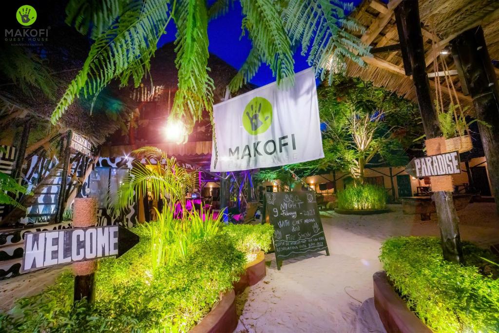 a restaurant with a welcome sign and some plants at Makofi Guest House in Nungwi