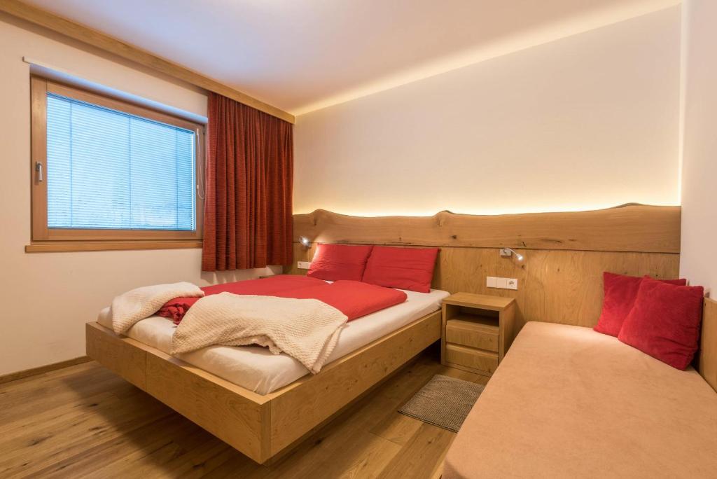 um quarto com 2 camas com almofadas vermelhas e uma janela em Ulrica - Apartment Kristyn em Ortisei