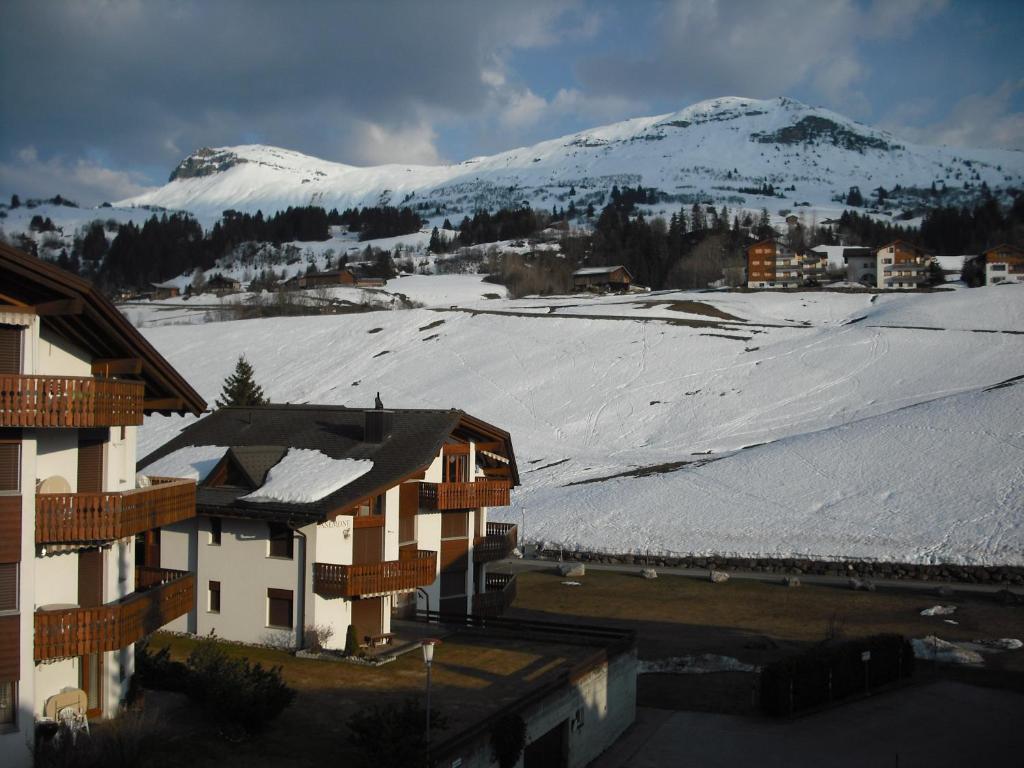 a snow covered mountain in a town with buildings at Ferienwohnung im Haus Primula in Obersaxen