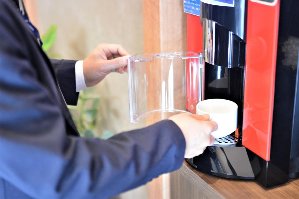 a person is using a coffee machine at LUXCARE HOTEL in Osaka