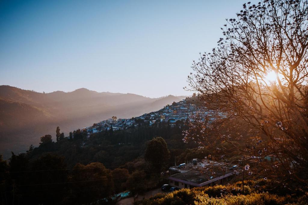 a view of a town on a hill with the sun setting at Hidden Heaven in Coonoor