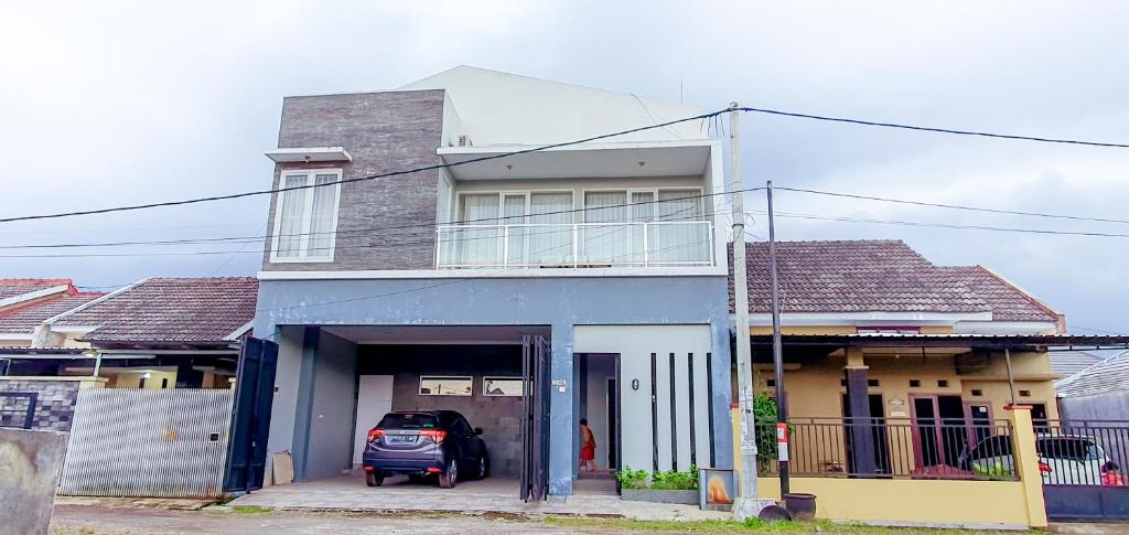 a house with a car parked in front of it at Villa Mangli Monochrome Syariah by eComerceloka in Jember