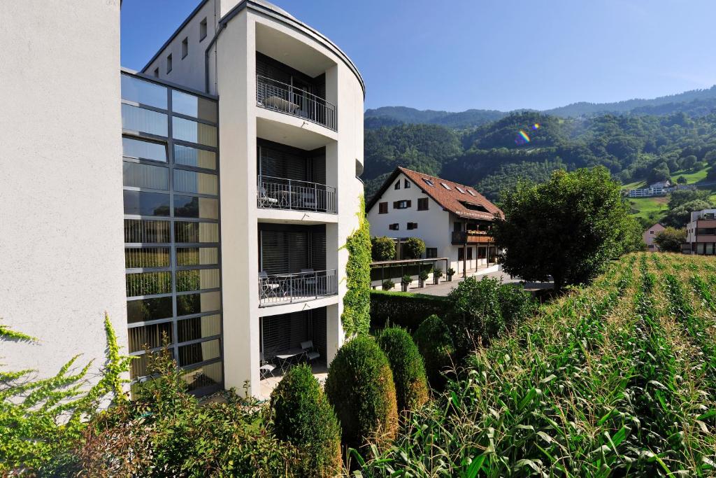 een wit gebouw bovenop een heuvel met struiken bij Hotel Schatzmann in Triesen