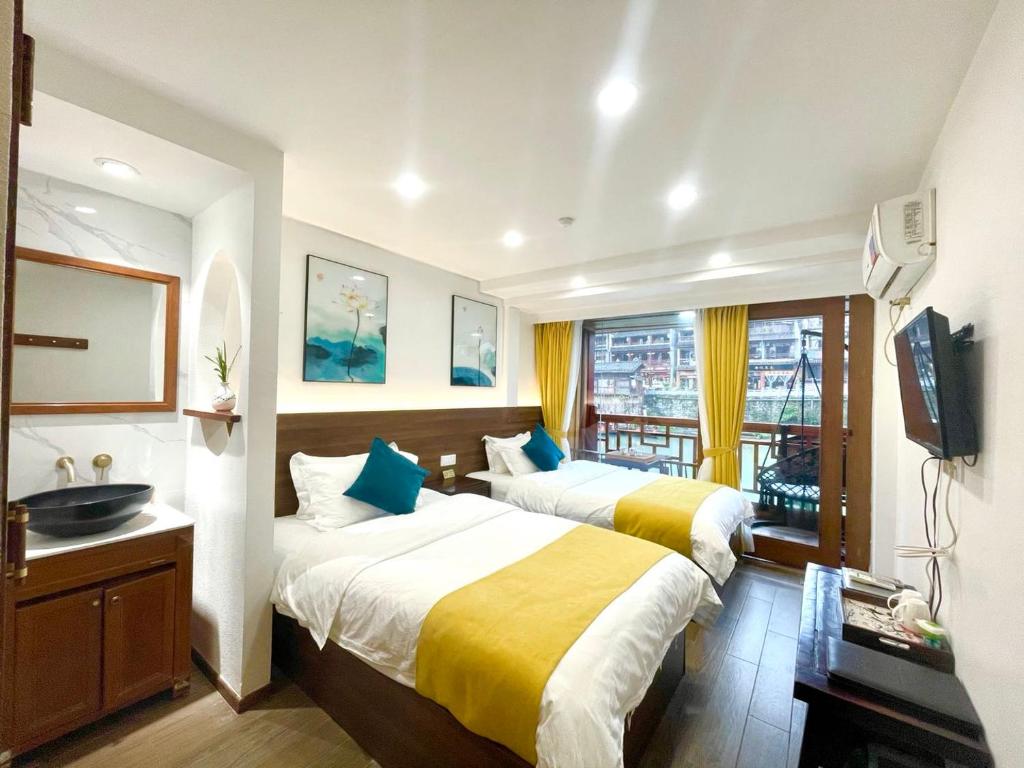 a hotel room with two beds and a television at Bian Cheng Xing Zi Inn in Fenghuang County