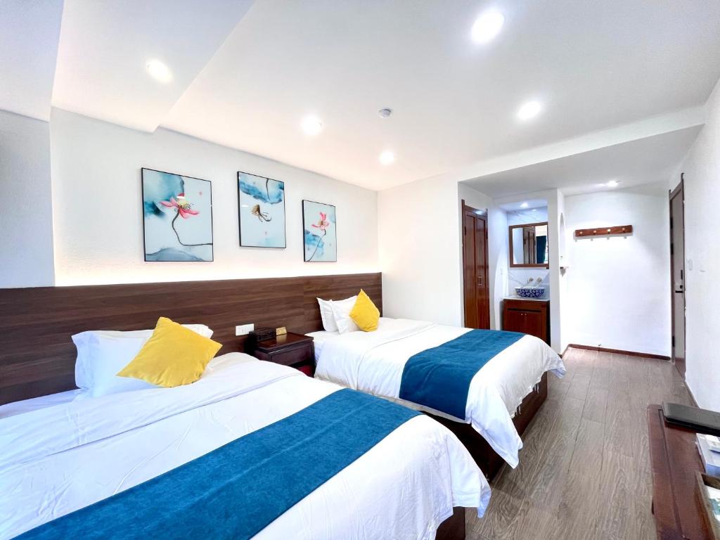 two beds in a hotel room with white and blue sheets at Bian Cheng Xing Zi Inn in Fenghuang County