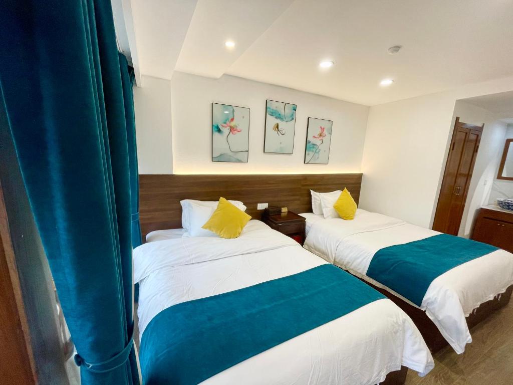 two beds in a room with blue curtains at Bian Cheng Xing Zi Inn in Fenghuang County