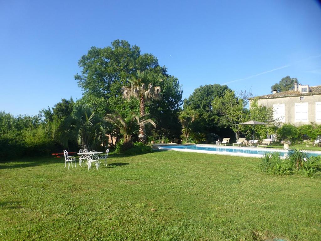 un patio con piscina y sillas y una casa en Domaine Sesquier Mas d'exception Iris, en Mèze