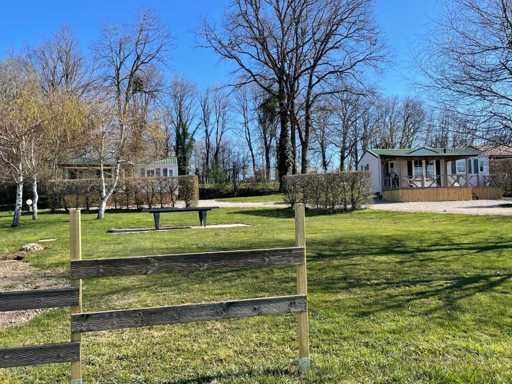 un parc avec une clôture en bois et une maison dans l'établissement Jura mobile home, à Marigny