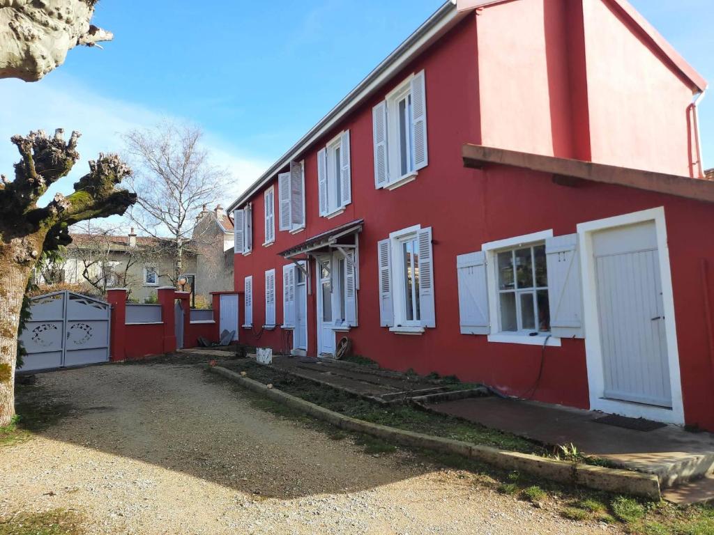 a red house with white doors and a yard at Les lunettes d'Oyo in Oyonnax