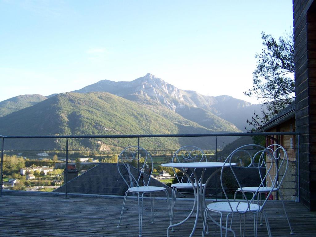 una mesa y sillas en un balcón con montañas en Le Baluchon, en Cierp