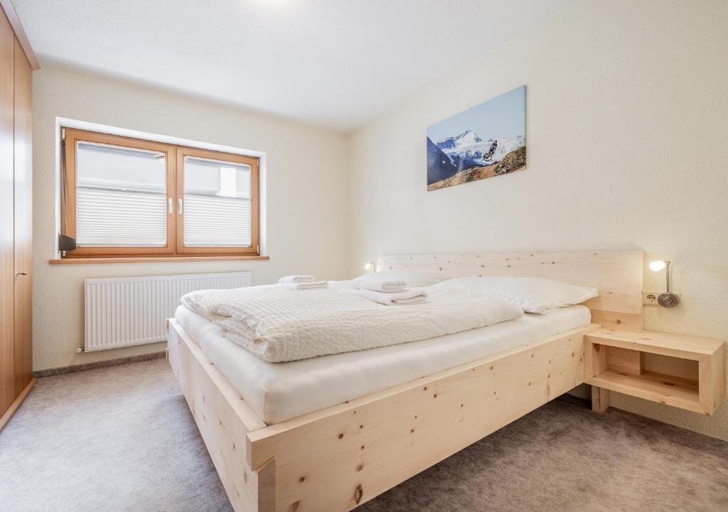 een slaapkamer met een houten bed en een raam bij Appartement Marlenka in Umhausen