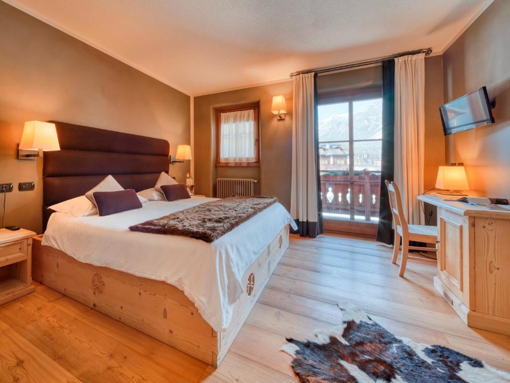 a bedroom with a large bed and a large window at Agriturismo Rini in Bormio