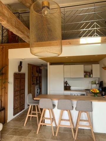 a kitchen with a counter with stools and a light at Domaine Sesquier Mas d&#39;exception Hibiscus in Mèze