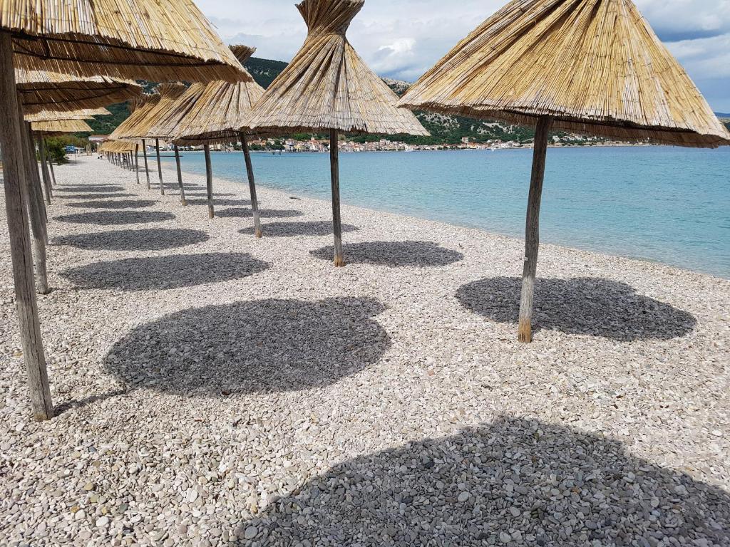 a row of straw umbrellas on a beach at Holiday house Maja in Baška