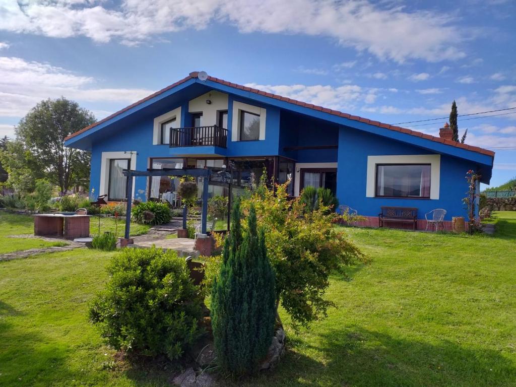 una casa azul con un patio verde en Son de Mar Hotel rural & Apartamento en Quintueles