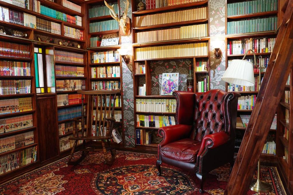 a library with a red chair in a room filled with books at 露伴ロハンrohan in Oshima