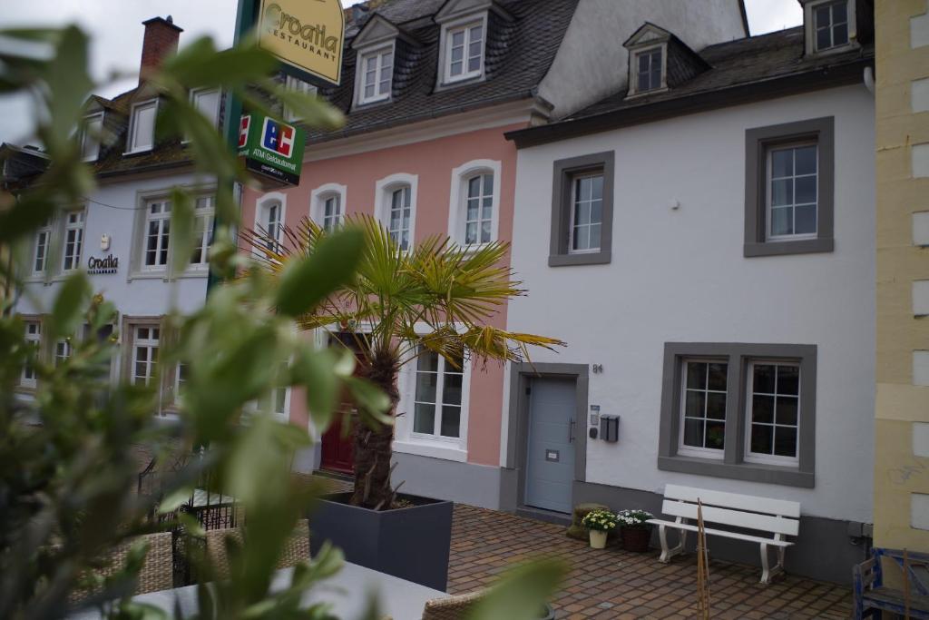 un bâtiment blanc et rose avec un palmier à l'avant dans l'établissement Wohnen am Ufer der Mosel in Trier, à Trèves