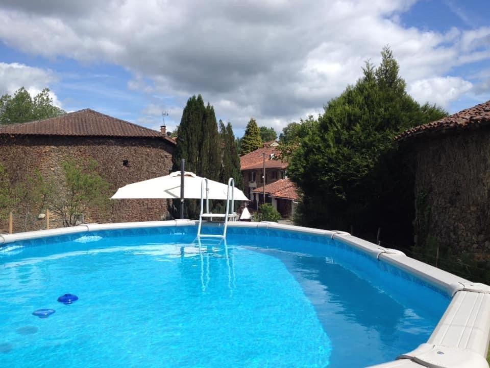 a large blue swimming pool with an umbrella at Le Jolie Grenier a Foin in Saulgond