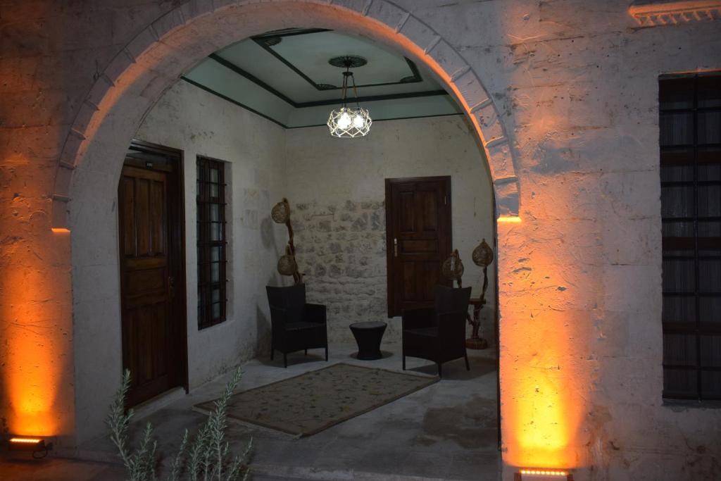 einen Torbogen in einem Gebäude mit Stühlen und Türen in der Unterkunft HASBAHAN KONUKEVİ&BUTİKOTEL in Şanlıurfa