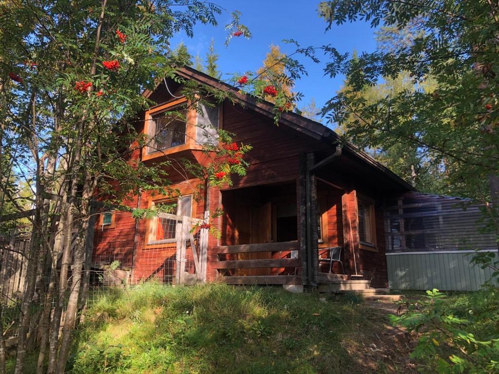 una vieja casa roja con un árbol delante en Aarnitupa, cottage by lake Kylmäluoma, 