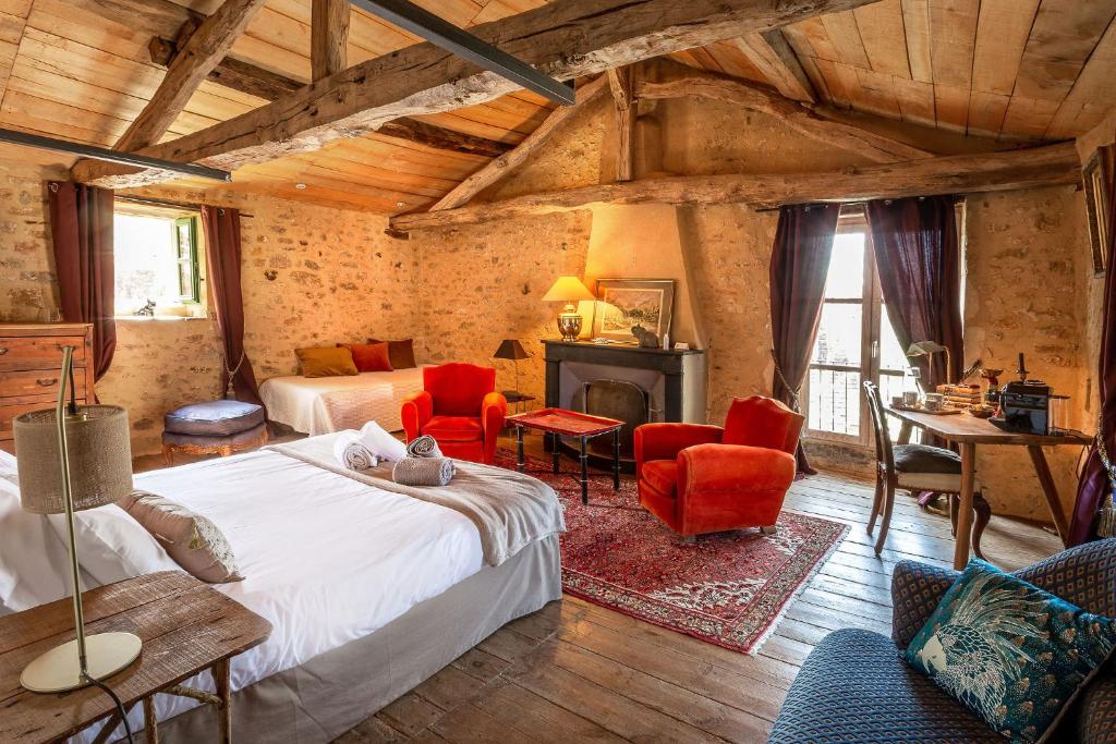 a bedroom with two beds and chairs and a fireplace at Villa Marguerite Chambres et Table d Hotes de charme in Cadouin