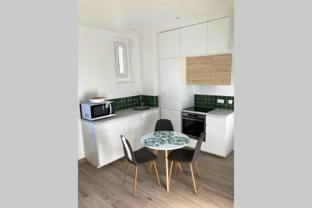 een keuken met een tafel en stoelen en een magnetron bij Appartement cosy proche RER et centre ville in Le Plessis-Robinson