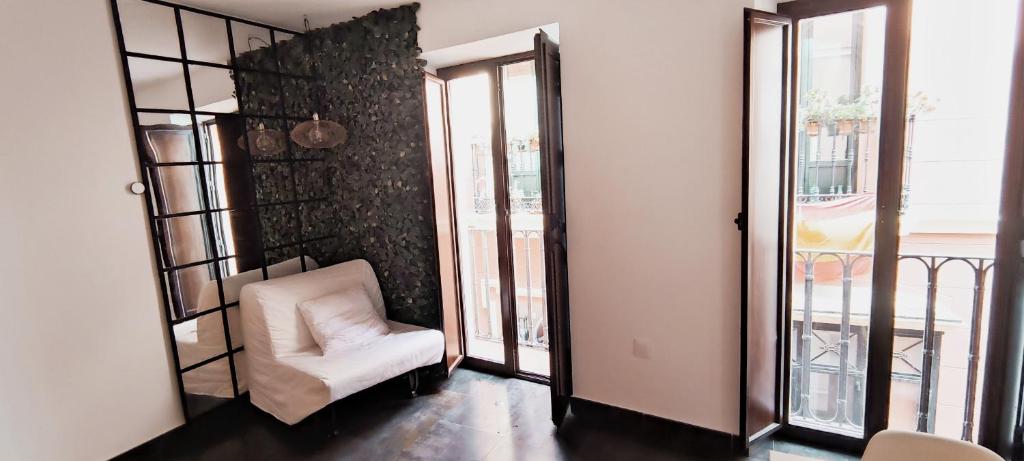 a living room with a white chair and windows at piso exterior centro sevilla in Seville