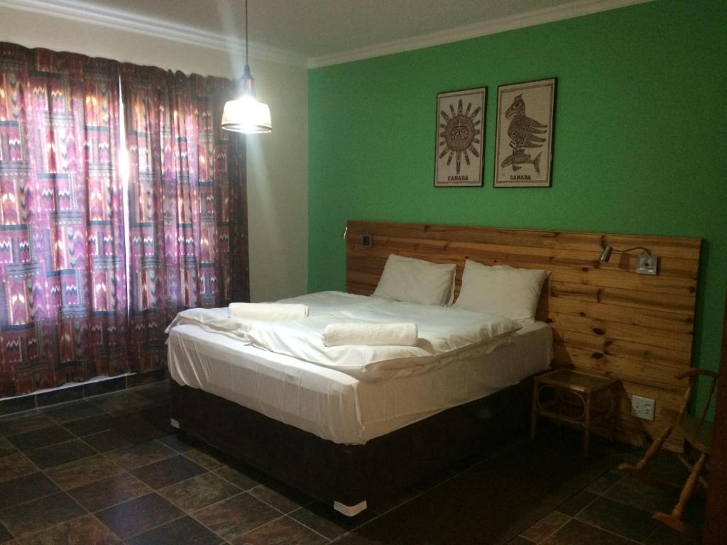 een slaapkamer met een groot bed met groene muren bij Edi's B&B and Bratwurst Sausage Restaurant in Balgowan