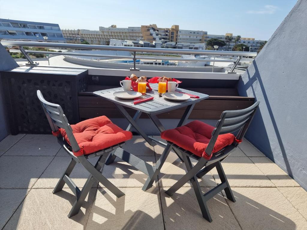 d'une table et de chaises sur un balcon avec une table et des boissons. dans l'établissement Le Cap d'Agde NATURISTE Grand T2 de standing avec GARAGE, au Cap d'Agde