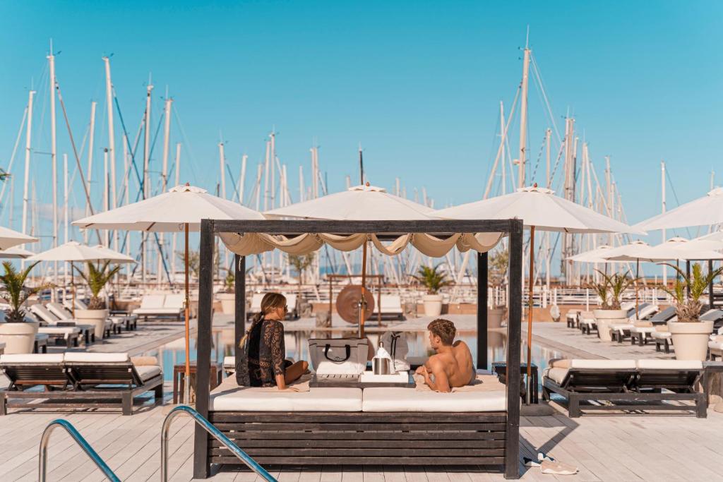two people sitting on a bed with umbrellas in a marina at Marina di Scarlino Resort in Puntone di Scarlino