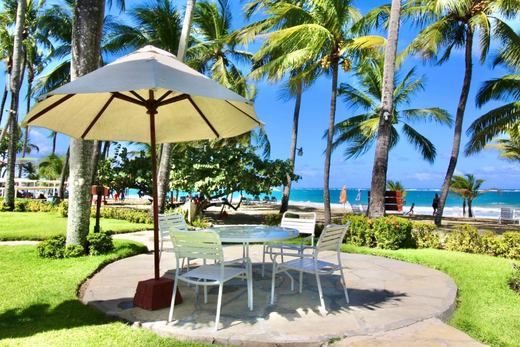 uma mesa e cadeiras debaixo de um guarda-sol perto da praia em Cabarete Palm Beach Condos em Cabarete