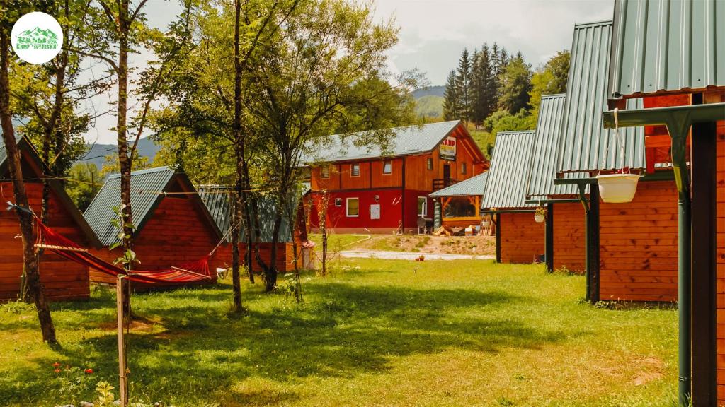 un grupo de graneros rojos y árboles en un patio en Camp Sutjeska, en Tjentište